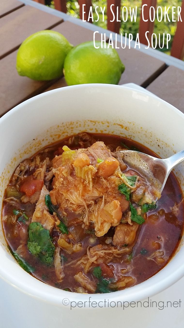 Crockpot chalupa soup in white bowl with two limes in background