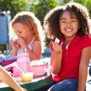 Elementary Pupils Sitting At Table Eating Lunch