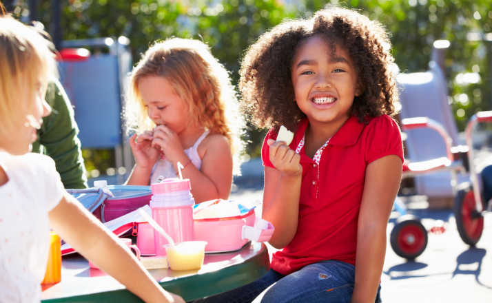 Elementary Pupils Sitting At Table Eating Lunch