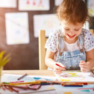 child girl draws with colored pencils in kindergarten