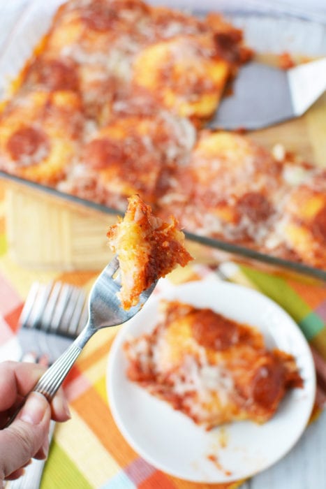 close up of pizza bake bite on fork with pizza bake in the background