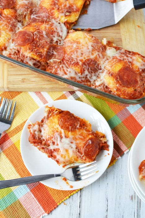 pizza bake in glass pan with plate and fork on checked table cloth