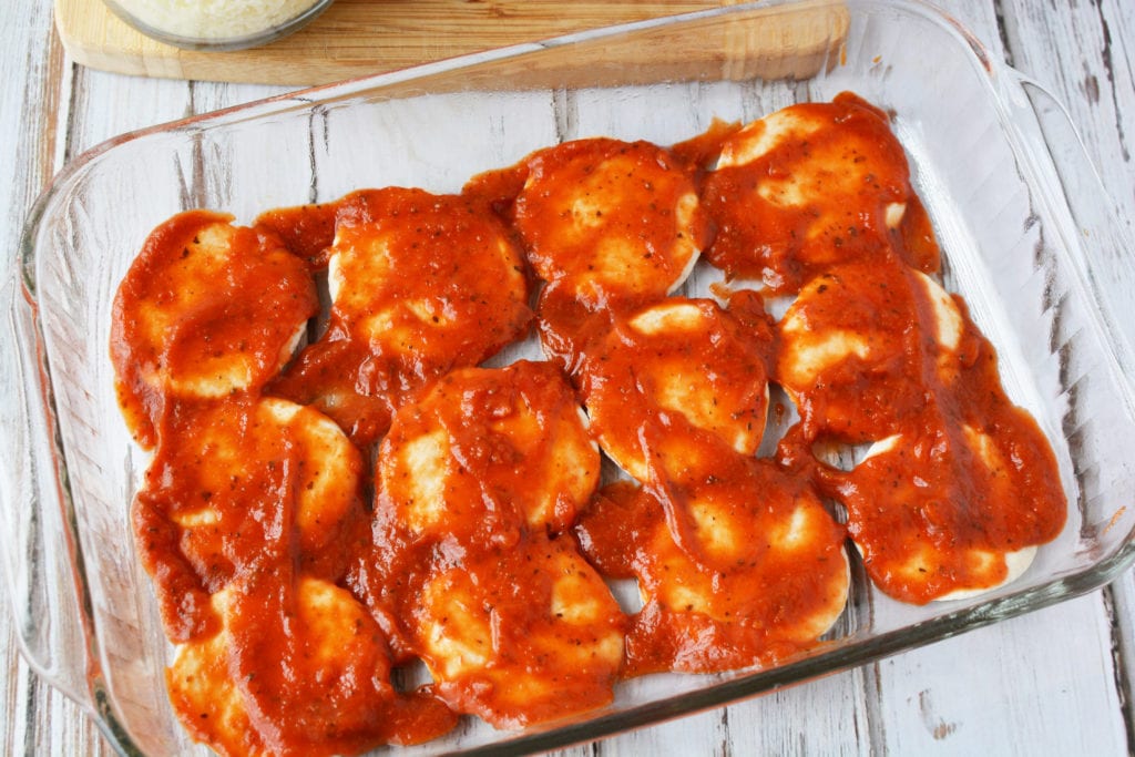 glass pan with biscuits and pizza sauce on top