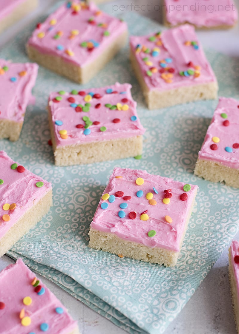 These frosted sugar cookie bars are THE BEST sugar cookie bars and an absolute must try! Between the sweet sugar cookie and the sweet fun frosting and sprinkles, these are such a delicious sweet treat! Not to mention they are some perfect soft and chewy cookie bars - my favorite type of cookie! Just scroll down below to find the full pan sugar cookie recipe! Super soft sugar cookies piled with delicious frosting and lots of sprinkles! Tastes just like a Lofthouse Sugar cookie, and so easy to bake since they're in bar form. #sugarcookie #sugarcookies #sugarcookierecipe #sugarcookiebars #cookierecipe #softsugarcookie #lofthousecookies