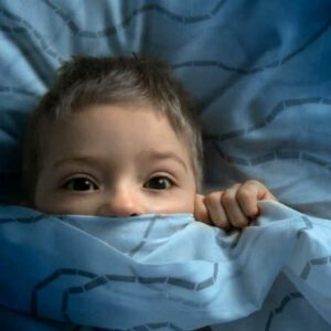 boy in bed with his eyes open. the child is afraid of the dark. tormented by nightmares and terrible dreams in children