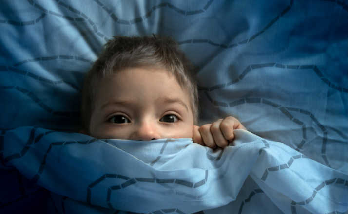 boy in bed with his eyes open. the child is afraid of the dark. tormented by nightmares and terrible dreams in children