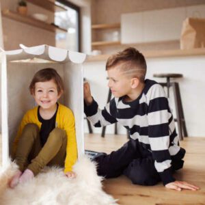 Two happy small children playing indoors at home.