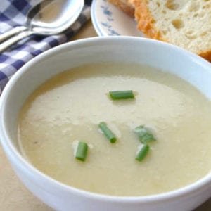 creamy potato leek soup in bowl with bread and spoon and napkin