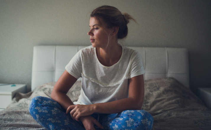 lonely woman sitting alone on bed