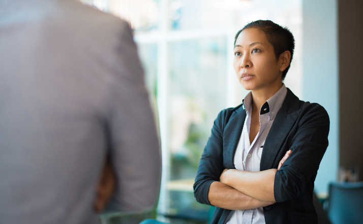 woman with arms folded talking to coworker