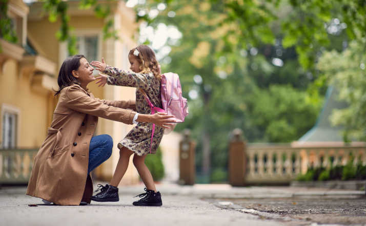 young businessmom hugging her little girl after school