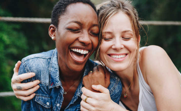 Happy female friends holding each other. 